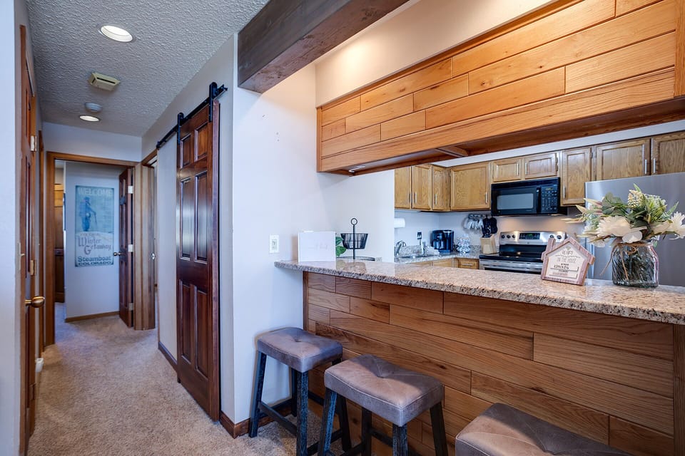 Your fully equipped kitchen features granite countertops, modern appliances, and bar seating—perfect for preparing meals and casual dining together.