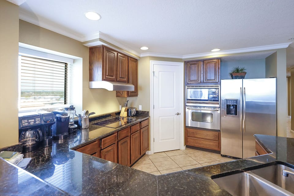 This kitchen features rich wooden cabinetry, modern stainless steel appliances, and a view of the surrounding landscape