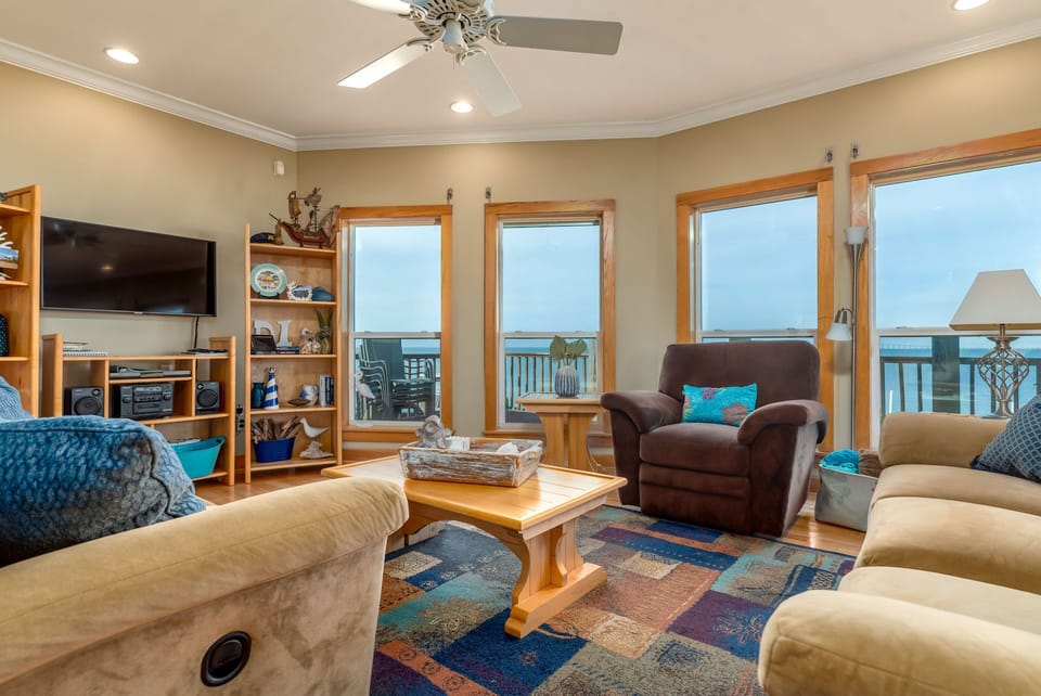 Sink into comfortable seating while enjoying your breathtaking oceanfront view through floor-to-ceiling windows in this beautifully appointed living space.