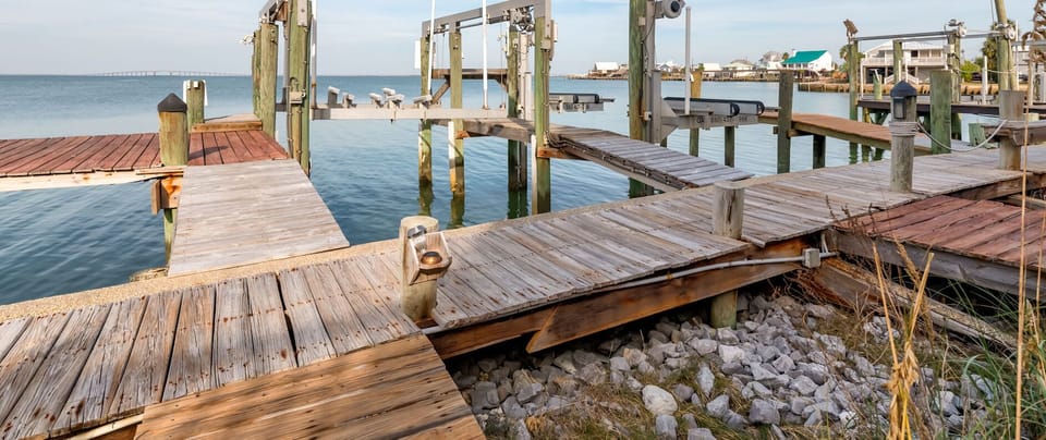 Marina setting with wooden docks and boat lifts extending over calm waterfront.