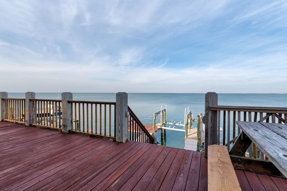 Waterfront deck with direct access to private dock and calm waters beneath expansive skies.