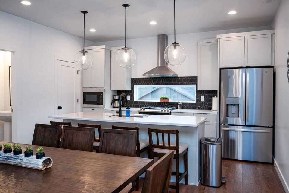 The gourmet kitchen features an island with seating for four and is equipped with brand-new stainless steel appliances, including a microwave, gas stove, and spacious refrigerator.