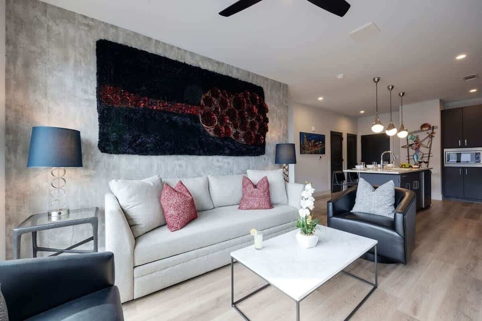 Modern open concept living area with floor to ceiling windows, designer furniture, smart TV, and access to private patio.