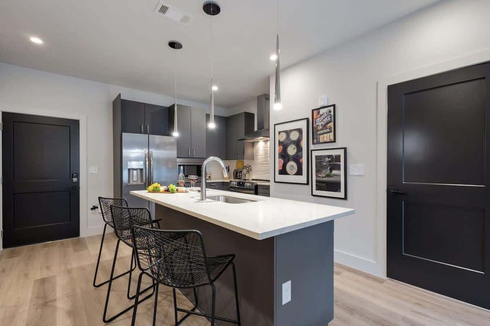 Fully equipped kitchen with stainless steel appliances, basic cooking essentials, toaster, coffee machine, and kitchen island seating.