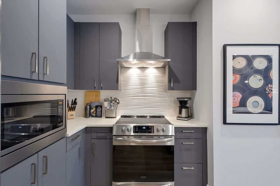 Fully equipped kitchen with stainless steel appliances, basic cooking essentials, toaster, coffee machine, and kitchen island seating.