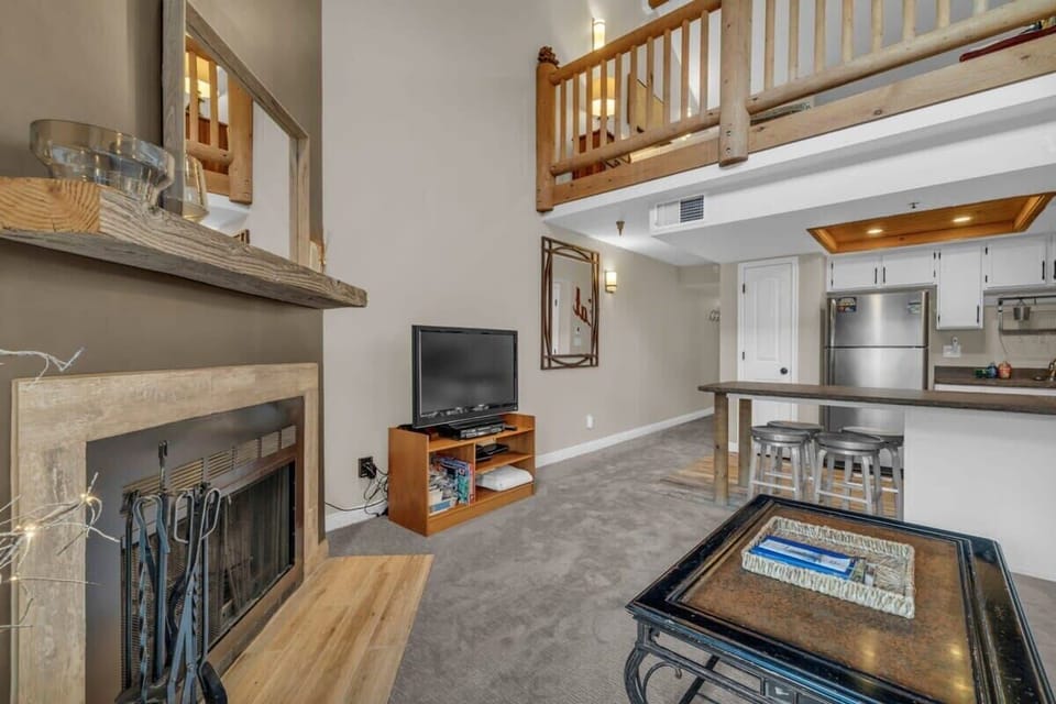 The home features an open and bright living room/kitchen/dining area, with high ceilings and large windows that look towards the ski slopes.