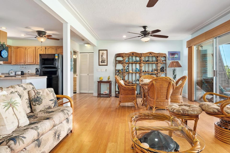 Relax in your tropical-themed living space with wicker furnishings, ceiling fans, and seamless indoor-outdoor flow through sliding doors.
