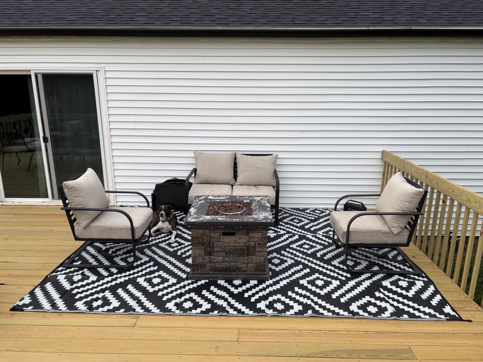 Deck has propane fire pit and sitting area with cushioned patio furniture. 
