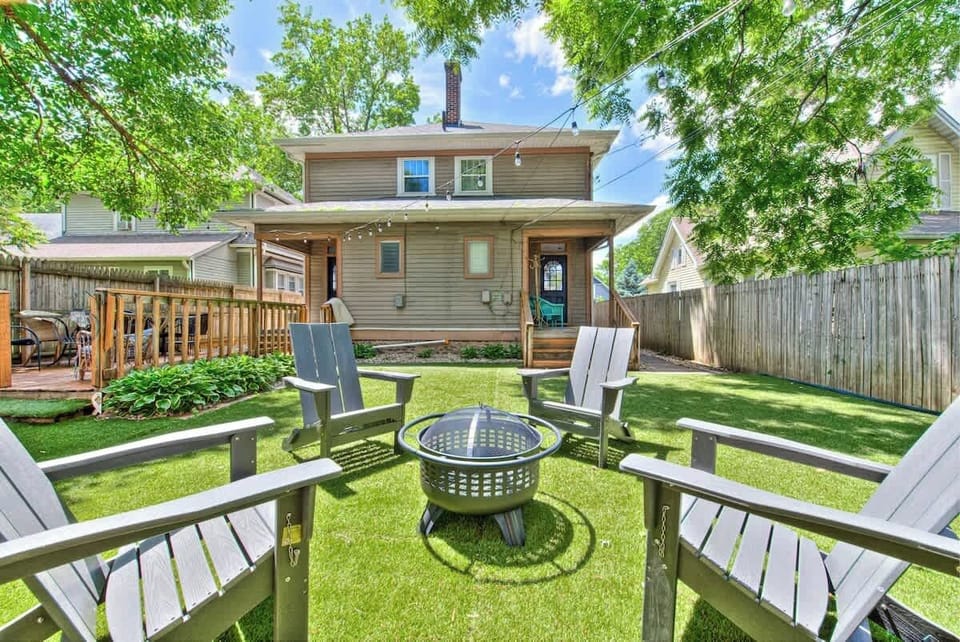 Charming Backyard with Fire Pit and Deck Unwind in this inviting backyard featuring a cozy fire pit surrounded by Adirondack chairs, perfect for evening relaxation. The private fenced yard includes a spacious deck with outdoor seating and lush greene