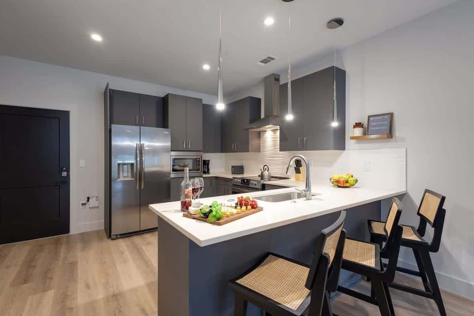 Fully equipped kitchen with stainless steel appliances, basic cooking essentials, toaster, coffee machine, and kitchen bar seating.