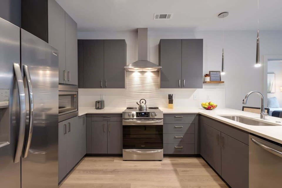 Fully equipped kitchen with stainless steel appliances, basic cooking essentials, toaster, coffee machine, and kitchen bar seating.