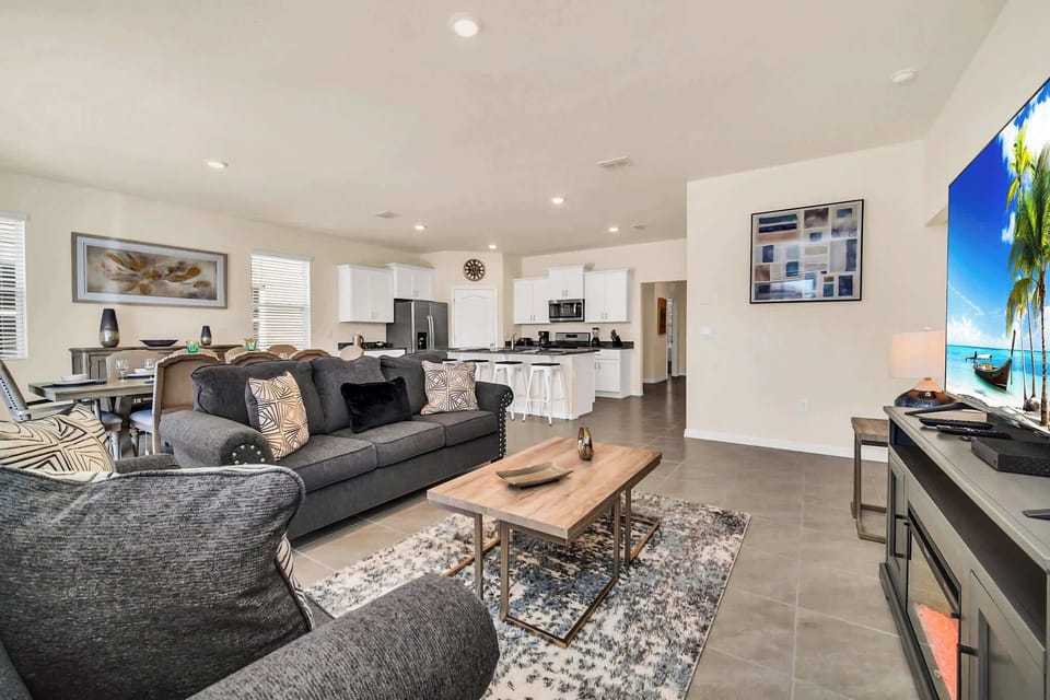 Relax in this spacious, stylish living room with a modern kitchen and entertainment setup, perfect for family gatherings.