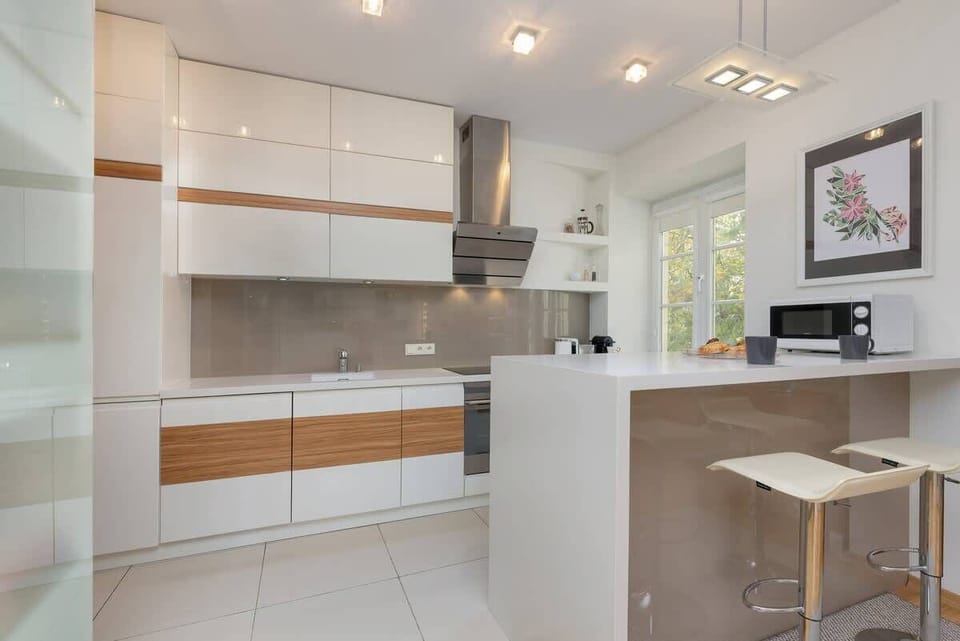 A modern kitchen featuring white and wooden cabinets, a breakfast bar, and built-in appliances.

