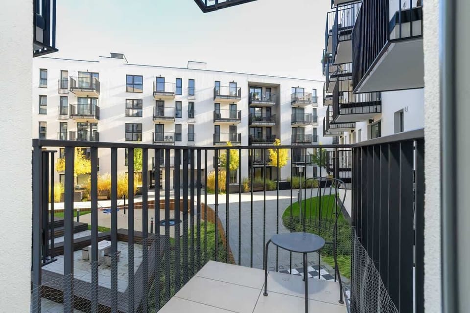 A balcony overlooking a modern residential courtyard with greenery.
