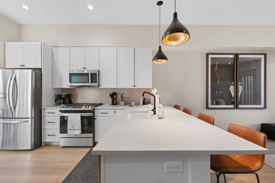 Your fully equipped kitchen awaits with stainless steel appliances, spacious island seating, and modern pendant lighting for memorable meal prep.