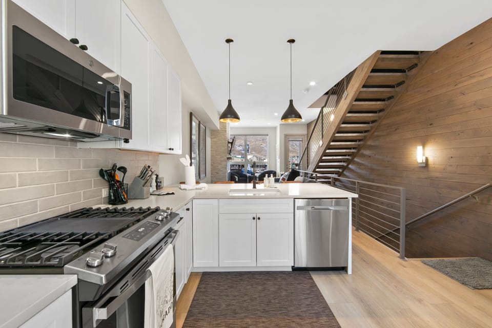 Your modern kitchen features sleek white cabinets, stainless steel appliances, and warm wood accents that create the perfect space for cooking memorable meals.