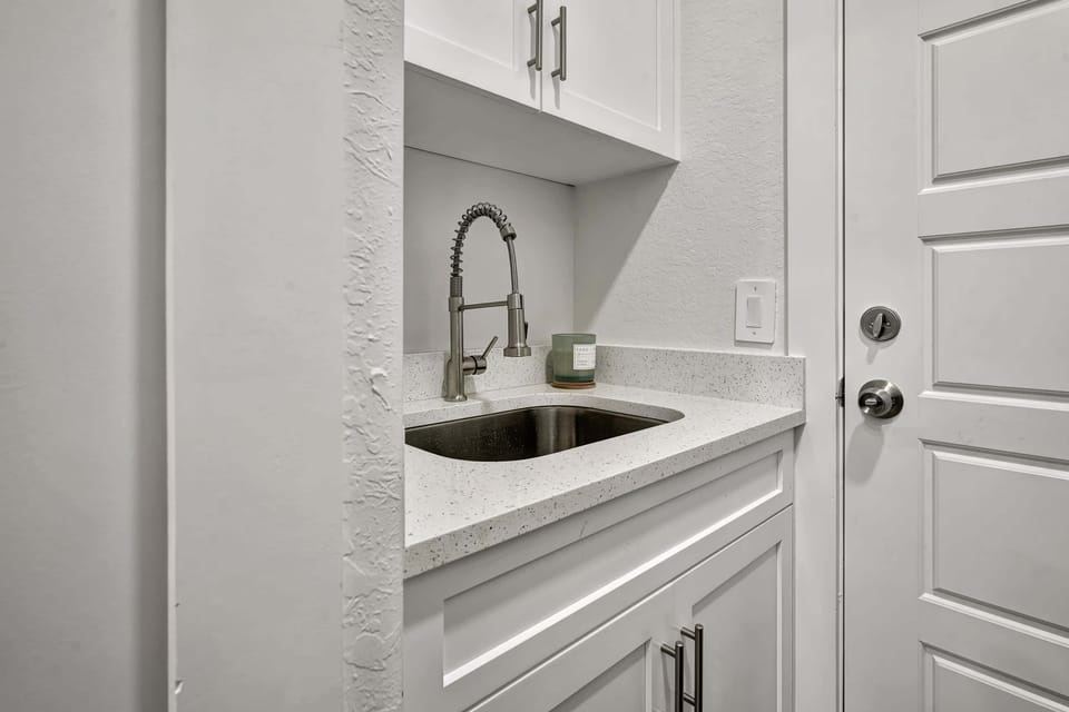 The laundry room includes a wash sink, the door leads to the garage