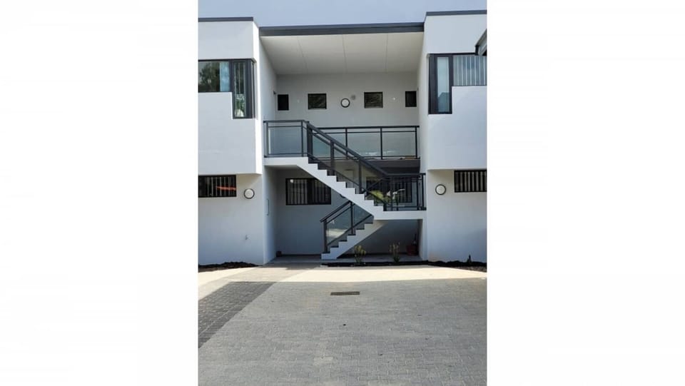 Discover our sleek and stylish property, featuring a modern facade and convenient staircase access to the upper levels. 