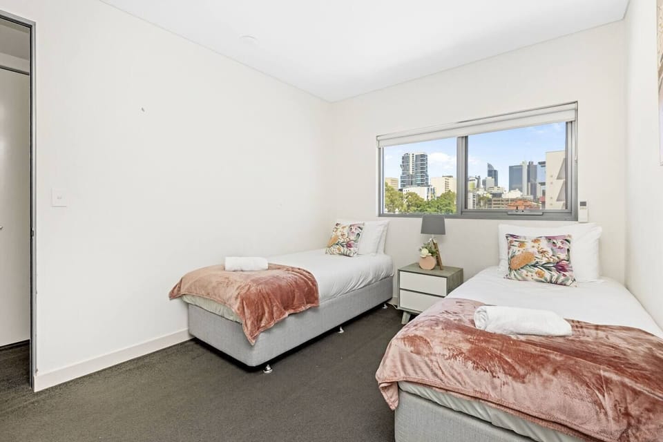 Twin bedroom with two single beds and city view.