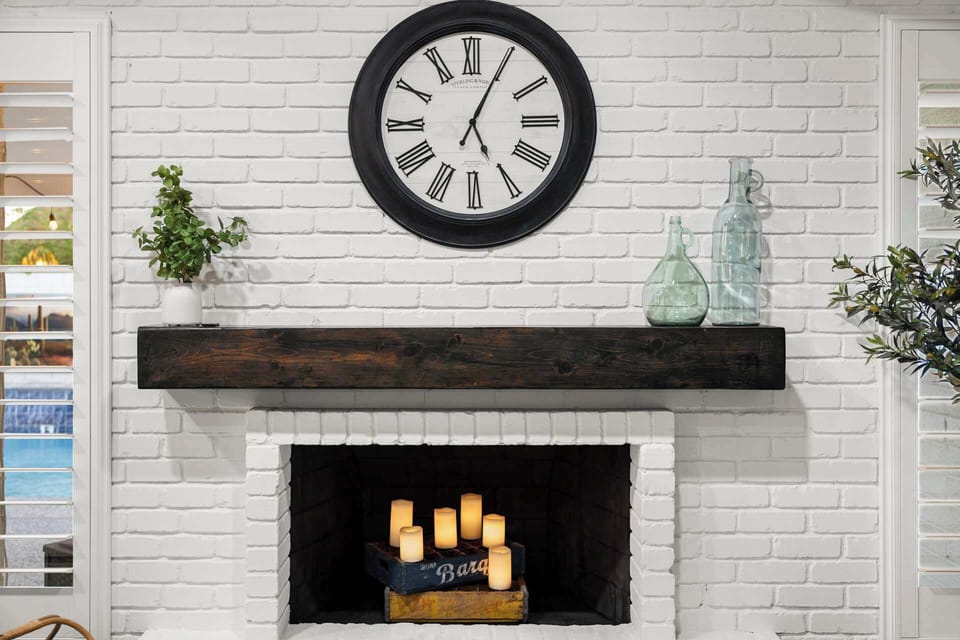 Elegant fireplace with a vintage clock and cozy candle arrangement.