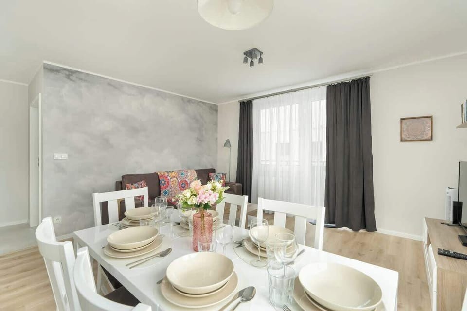 Another view of the living and dining area, this time showing the dining table with a vase of flowers and a comfortable seating area in the background.