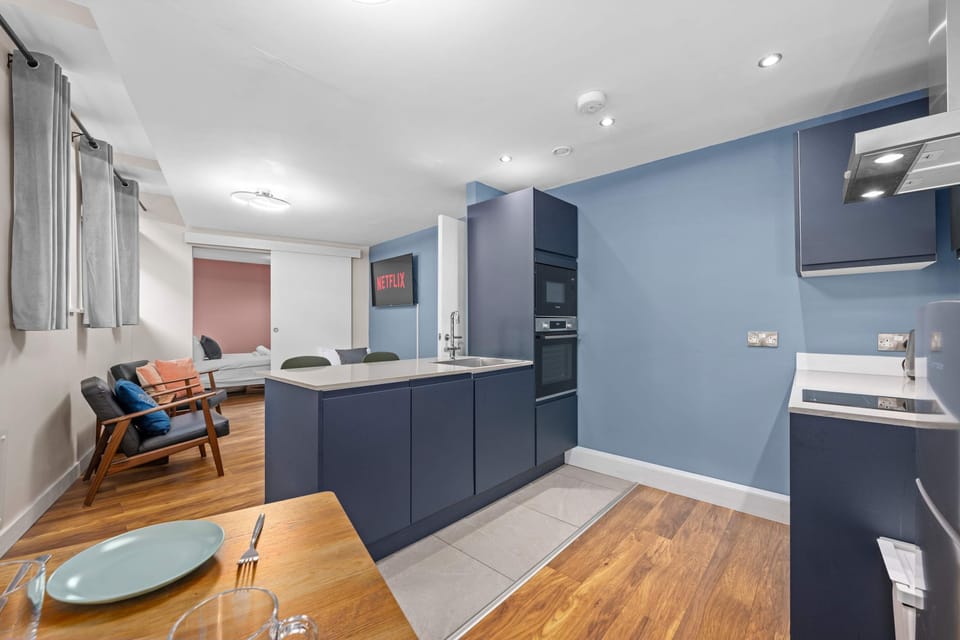 Modern kitchen with sleek blue cabinetry, built-in oven and dining space flowing into the living area