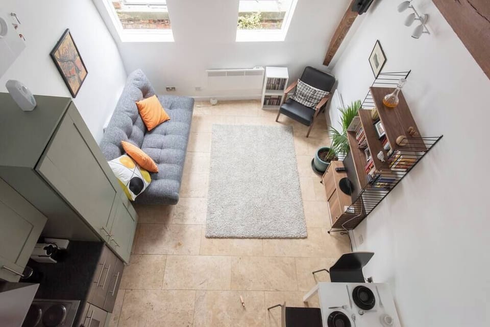 A birds-eye view of the living area from upstairs, showcasing the stunning double-height ceilings and original warehouse beams