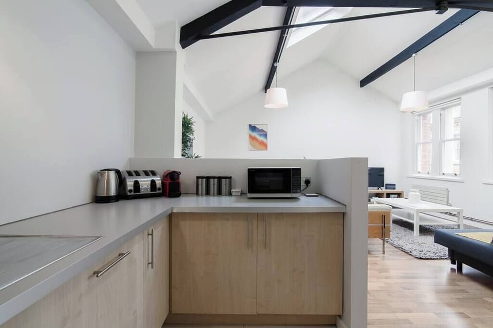 Bright open kitchen with microwave, kettle, and toaster, flowing seamlessly into the living space