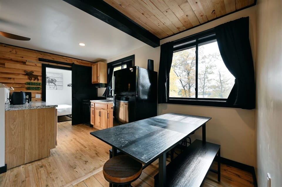 Modern kitchen with light wood cabinets, marbled countertops, a black sink, and a black ceiling fan.