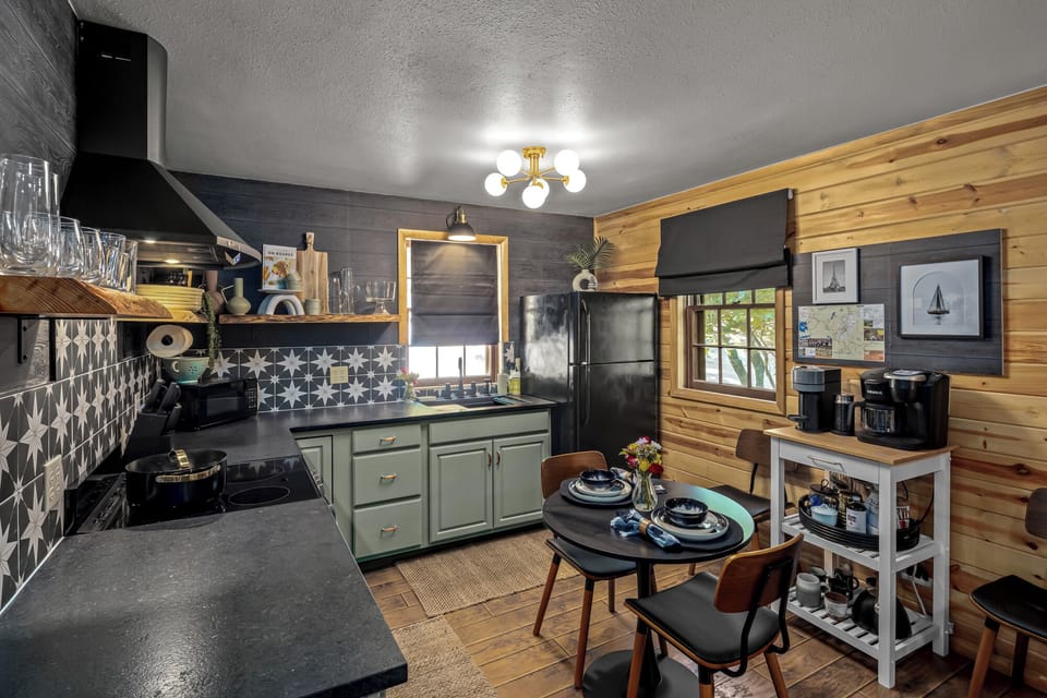 Prepare a romantic breakfast in this modern kitchenette featuring a full coffee station and stylish starburst tile. The smart layout includes a microwave, fridge, and an intimate dining table perfect for a quiet meal together.