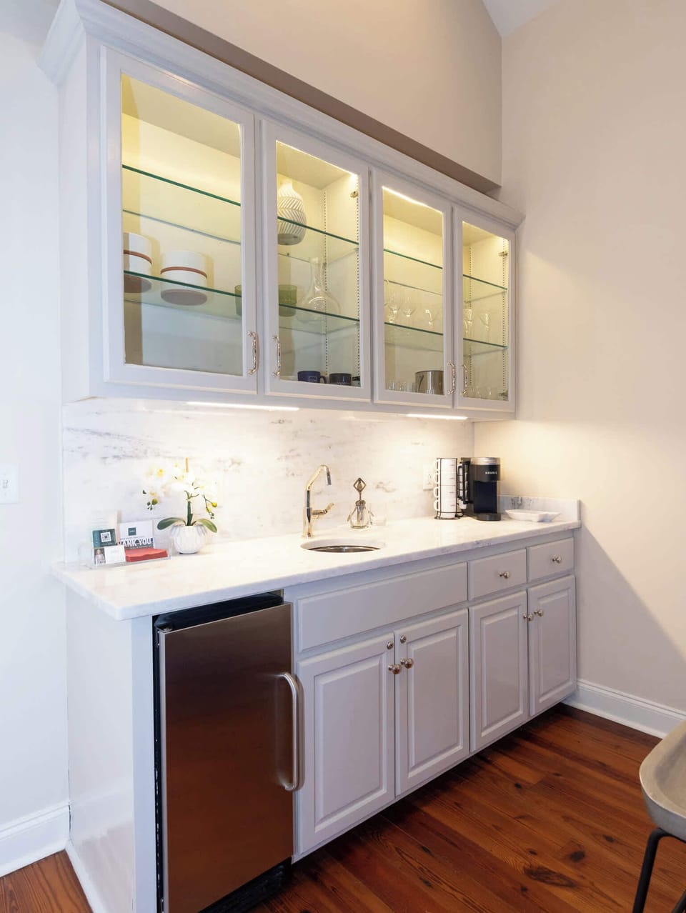 A detailed view of the wet bar setup, featuring glass-front upper cabinets and ample counter space for entertaining.
