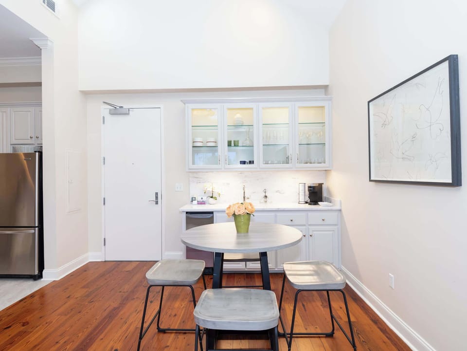 A stylish dining nook or social space featuring a marble-topped high table and a built-in wet bar in the background.