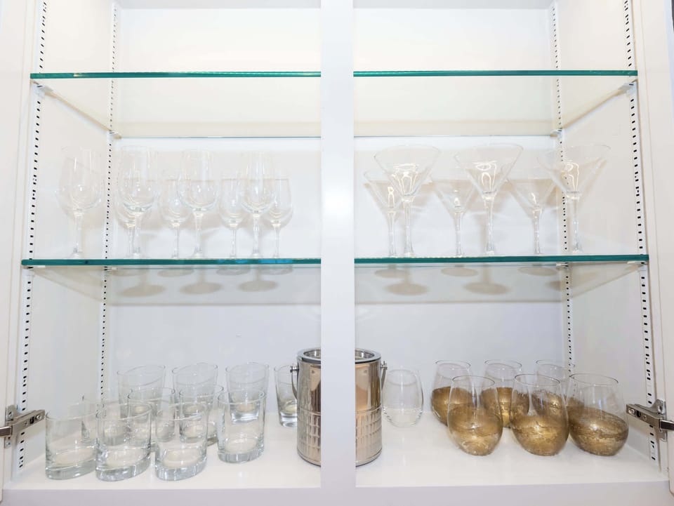 A detailed interior view of the glass-front cabinetry showcasing a neatly organized collection of glassware and bowls.