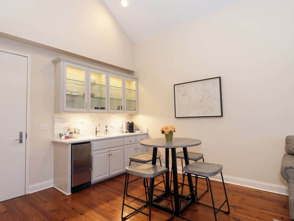 A dedicated beverage station area with clean white cabinetry and a built-in mini-fridge beneath a bright window.