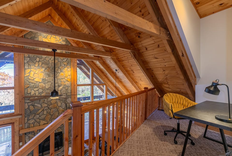 Work from the mountains in style. The loft overlooks a soaring stone fireplace wall framed by exposed timber beams.