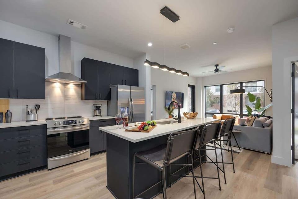 Fully equipped kitchen with stainless steel appliances, basic cooking essentials, toaster, coffee machine, and kitchen island seating.