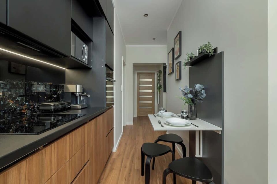 A view down the hallway connecting the kitchen and dining area with the rest of the apartment, featuring warm wood accents.

