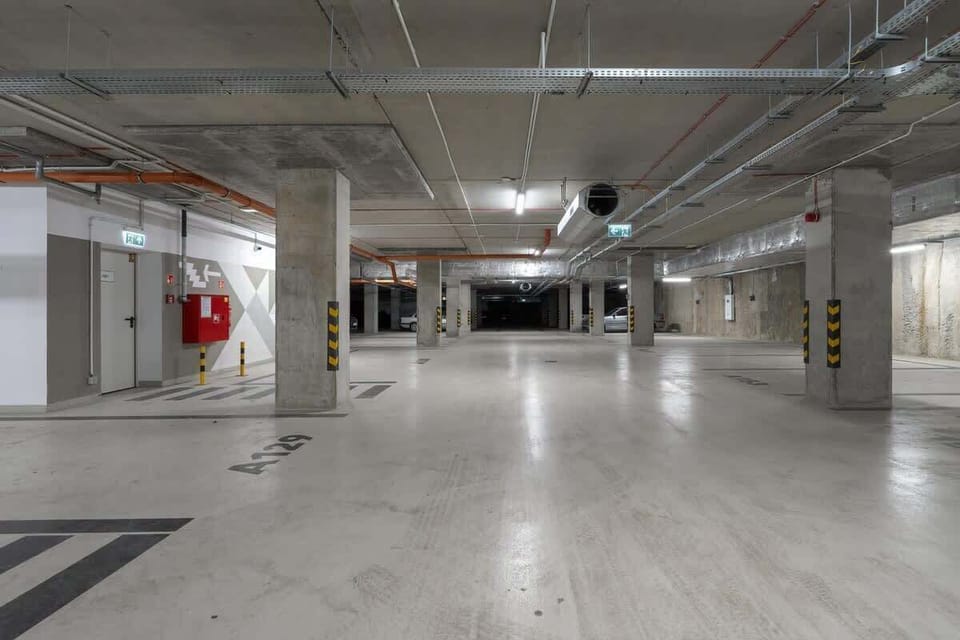 A spacious underground parking garage with well-marked parking spaces, bright lighting, and a clean, organized layout.






