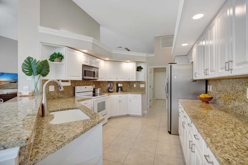 A long view of the kitchen showcasing the granite counters and stainless steel appliances