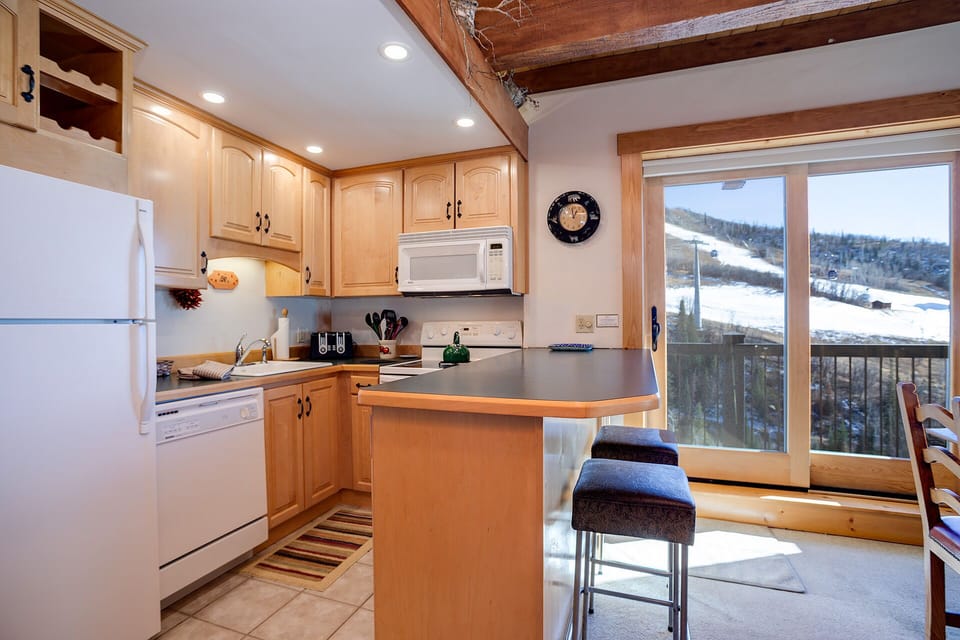 Whip up your favorite meals in this warm kitchen with exposed beams and stunning mountain views through the sliding door.