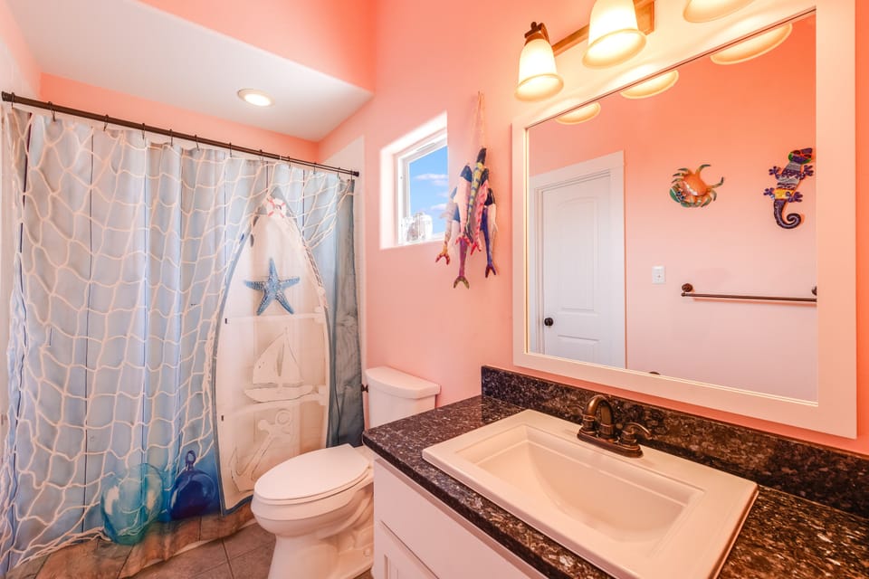 Dive into coastal charm in your vibrant bathroom, featuring playful sea-themed decor and warm coral walls that make every moment feel like a beach getaway.