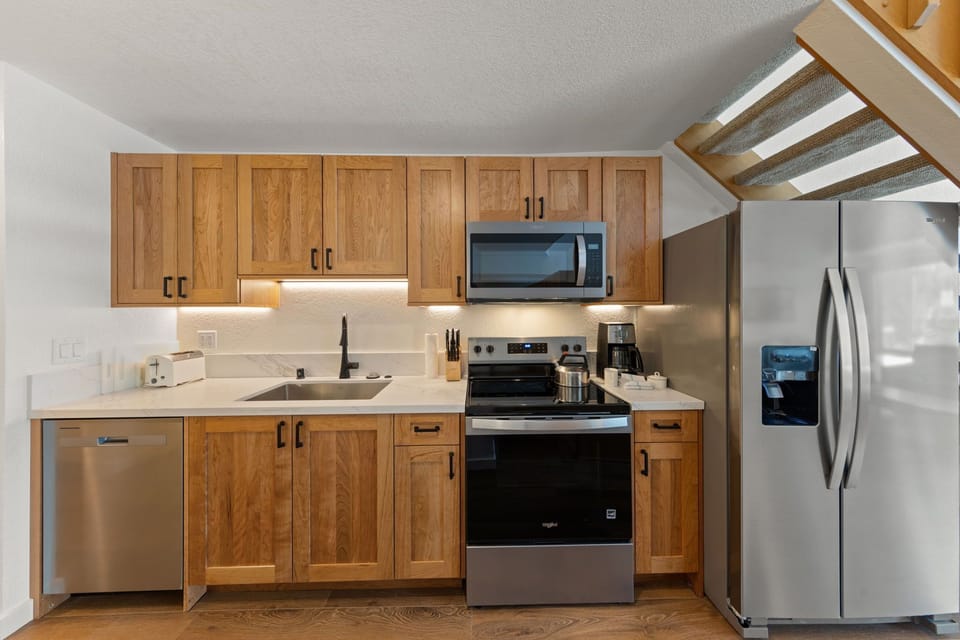 Your fully equipped kitchen features warm wood cabinetry and stainless steel appliances, perfect for preparing meals during your stay.