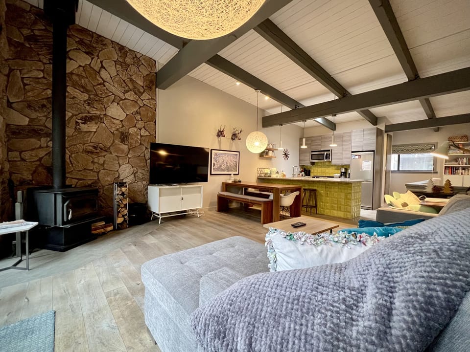 Living room with large flatscreen TV and wood burning stove.