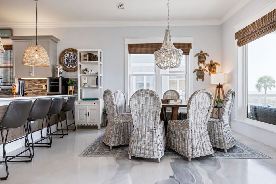 Gather around your stunning dining table where coastal elegance meets comfort, surrounded by wicker chairs beneath a gorgeous chandelier.