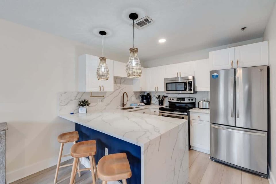 - Cook, chat, or snack in this gorgeous kitchen with marble style counters & bar stools - Stainless steel appliances, pendant lighting, & a bold blue island add flair - Whether you’re prepping meals or mixing drinks, everything’s right where you need