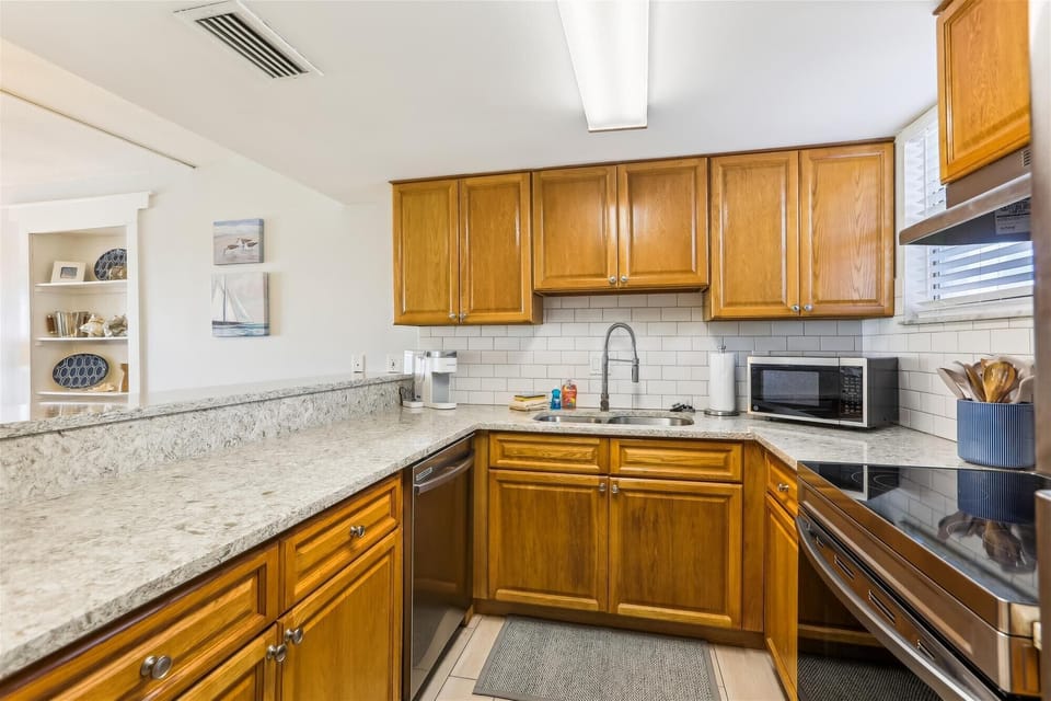 - Whip up fresh meals in this fully equipped kitchen featuring rich wood cabinetry and sleek stone counters
- Includes microwave, dishwasher, electric cooktop, and deep sink for easy cleanup
- Ideal for home cooked dinners or quick beach day snacks
