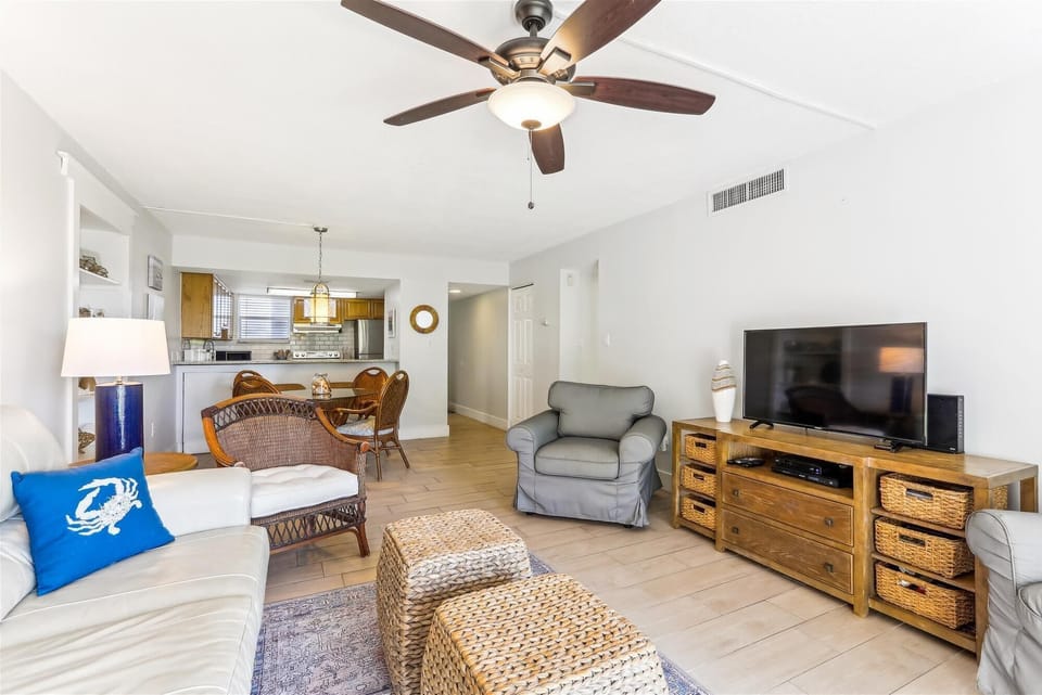 - Open layout connects living room to kitchen & dining, perfect for entertaining or relaxing with family
- Enjoy a mix of cozy seating, rattan textures, & wood accents for a beach feel
- Ceiling fan & soft lighting keep the space cool & inviting