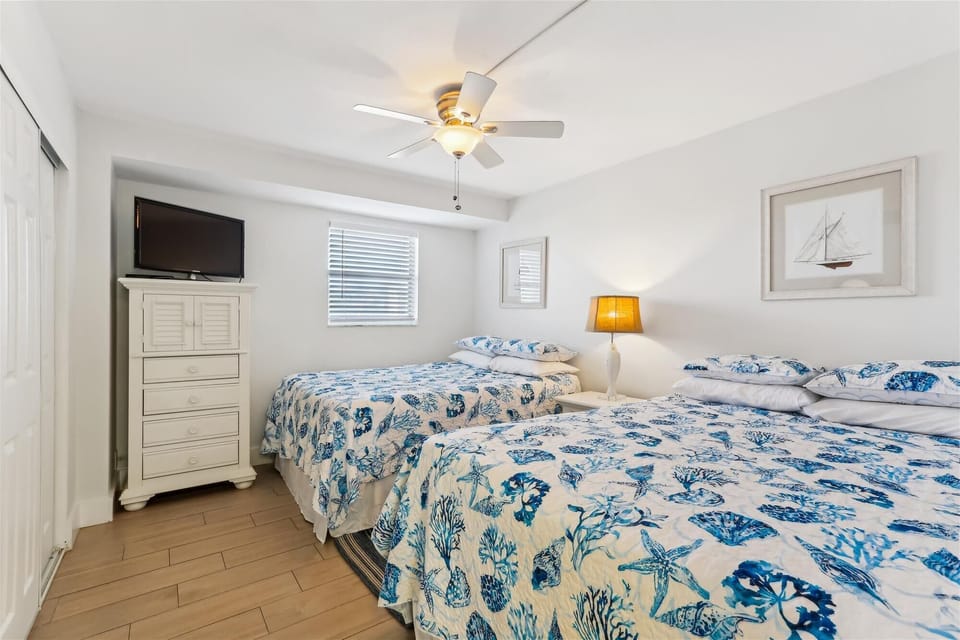 - Perfect for families or groups, this bedroom features two full size beds with sea inspired bedding
- Enjoy a flat screen TV, tall dresser, and windows that bring in natural light
- Ceiling fan and reading lamp ensure a cool and cozy retreat