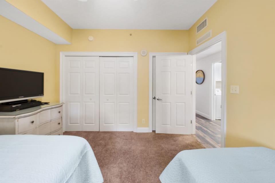 Relax in your spacious bedroom featuring two comfortable beds, flat-screen TV, and ample closet storage for all your belongings.