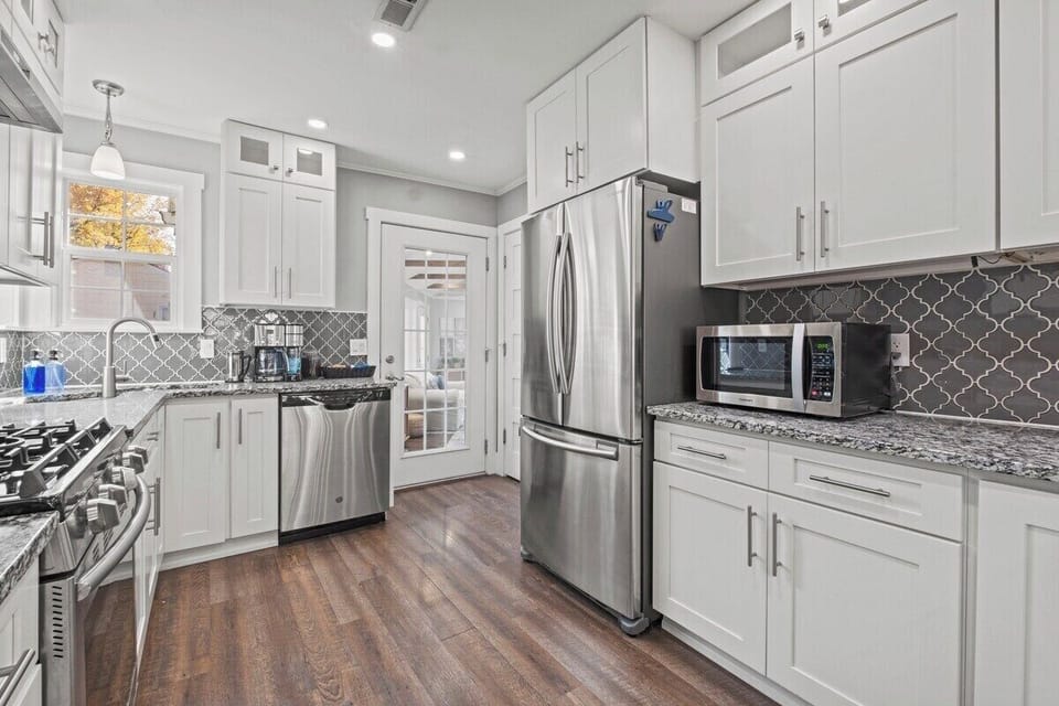 Bright, fully equipped kitchen with stainless steel appliances, white cabinetry, and plenty of counter space for cooking at home in Mission, KS.